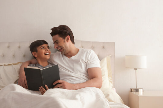 Father and son reading book together