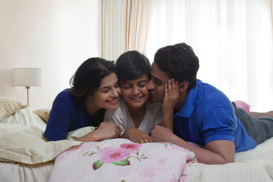 Parents kissing son in bedroom
