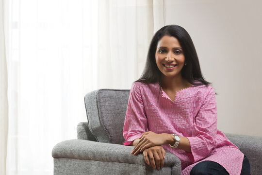 Portrait of cheerful woman sitting on sofa