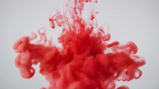 Red ink cloud diffusing in clear liquid, symbolizing imagination, resilience, artistry, harmony, transformation, brilliance, mystery, authenticity, inspiration.