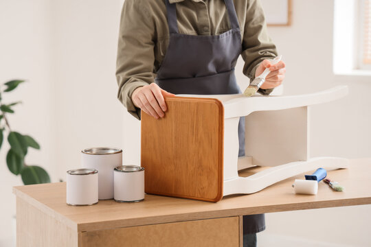 Person painting a wooden stool white, home improvement and furniture restoration project, diy hobby and creative activity