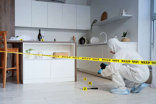 Forensic expert in protective suit examining crime scene evidence in a modern kitchen with Yellow tape, Yellow keep out tape cordons off the area, indicating a crime scene investigation