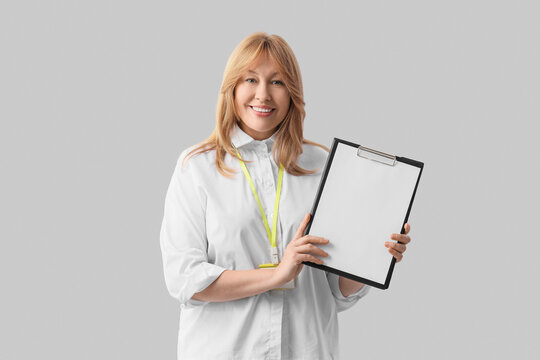 Female bank manager with blank clipboard on light background