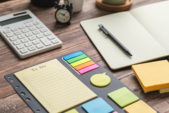 to do list notepad with colorful sticky notes calculator notebook and alarm clock on wooden desk