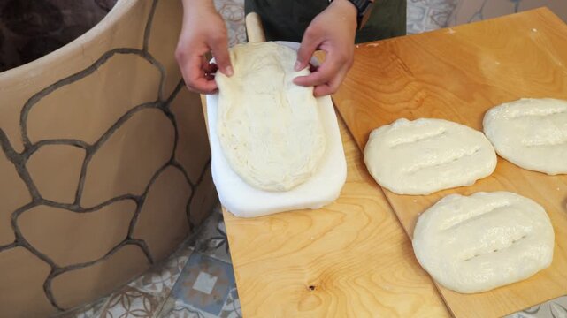 A close-up of a male chef preparing traditional bread in a tandoor. He spreads the flatbread on a special pillow, while the concept of catering to traditional Asian cuisine is being demonstrated. 
