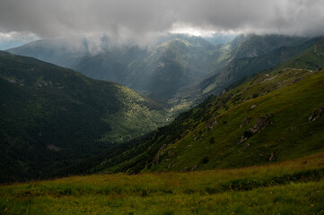 Fototapeta premium Sunbeams breaking through clouds over a green mountain valley