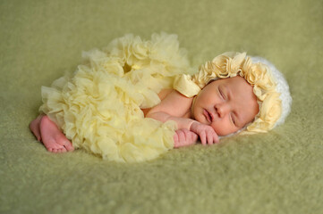 Obraz premium Newborn baby girl sleeping in yellow ruffled dress