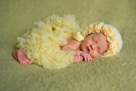 Newborn baby girl sleeping in yellow ruffled dress