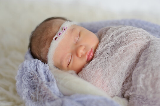 Swaddled newborn baby girl sleeping peacefully