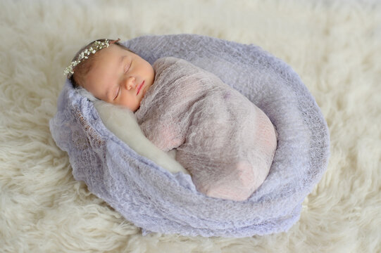 Peaceful newborn baby wearing flower headband sleeps