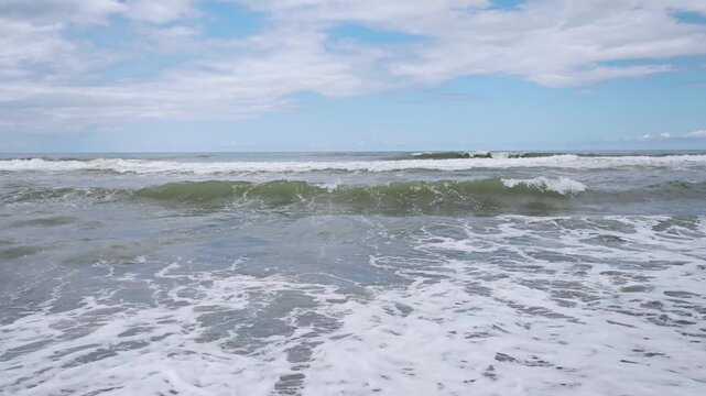 Rough Sea Waves Rolling onto Empty Dark Sand Shoreline on Cloudy Day