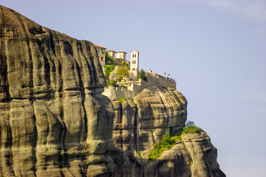 The Holy Monastery of Great Meteoron, perched atop a towering rock formation in Meteora, Greece, under a clear blue sky.