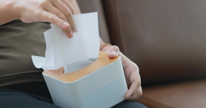 Hand pulling a tissue from a tissue box, tissue box, hygiene and cleanliness, healthcare, daily living, home essentials, and personal care, close-up