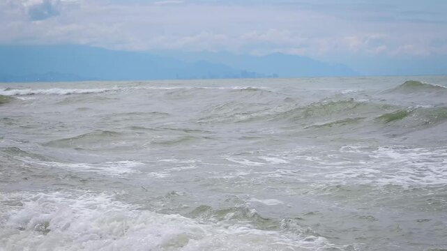 Rough Sea Waves Rolling onto Empty Dark Sand Shoreline on Cloudy Day