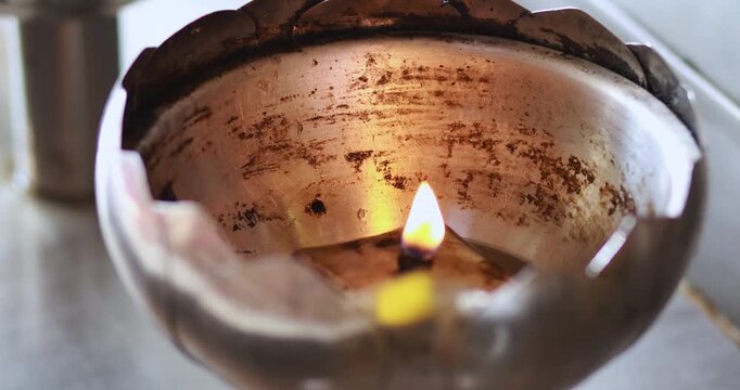 Oil lamp flame burning in a metal holder with a warm glow. Ideal for light, spirituality, tradition, meditation, hope, ceremony, and peaceful atmosphere concepts, close-up