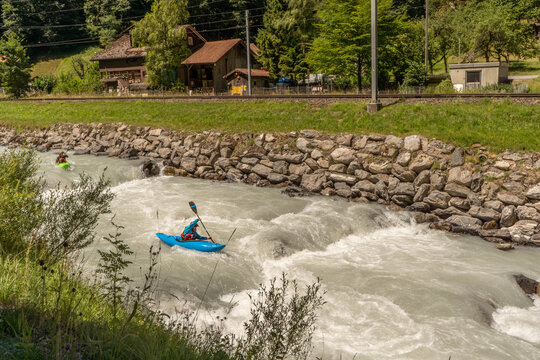 Action photograph of a kayakers paddling through turbulent whitewater surrounded by rugged alpine scenery and glacial river currents.