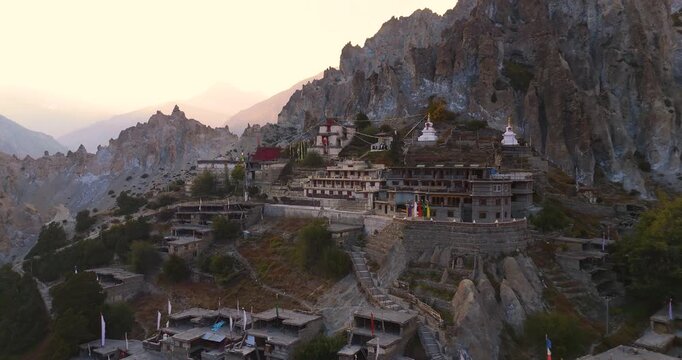 Annapurna Circuit, Manang Nepal, aerial push-in shot toward ancient Bhraka Monastery and traditional stone buildings built into rugged mountain cliff