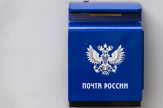Blue Russian Post Mailbox with Postal Emblem on Building Wall.