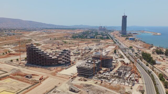 Aerial view of a massive construction site with numerous buildings under development. Including a modern skyscraper next to the sea