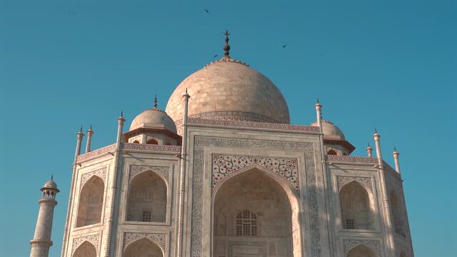 A low-angle view showcases the central dome, chhatri kiosks, and intricate marble inlay work of the Taj Mahal in Agra.