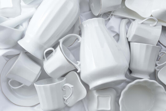 Various white ceramic kitchenware on white fabric.