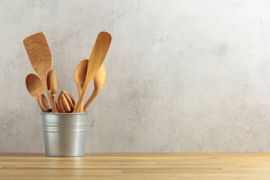Wooden kitchen utensils in small bucket on a kitchen table.