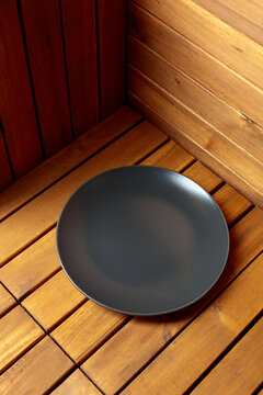Empty black plate on natural wooden background.