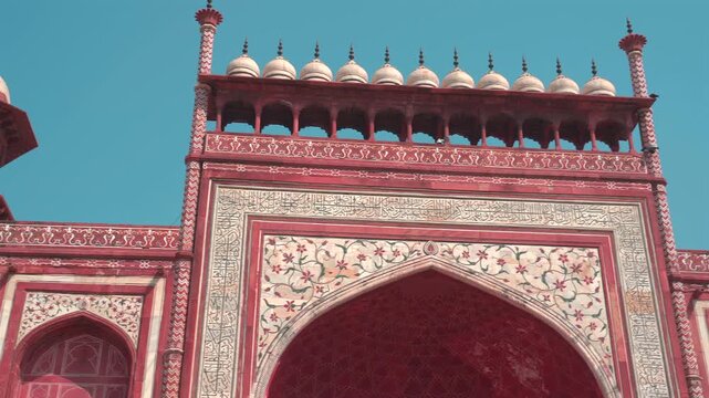A slow panning shot highlights the intricate white marble inlay, floral motifs, and decorative domes of the Taj Mahal main entrance gate in Agra.