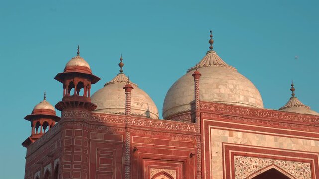 Warm sunlight illuminates the white marble domes and red sandstone turrets of the Kau Ban Mosque at the Taj Mahal complex in Agra.