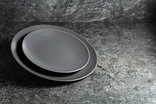 Empty round black plates on a black stone background.