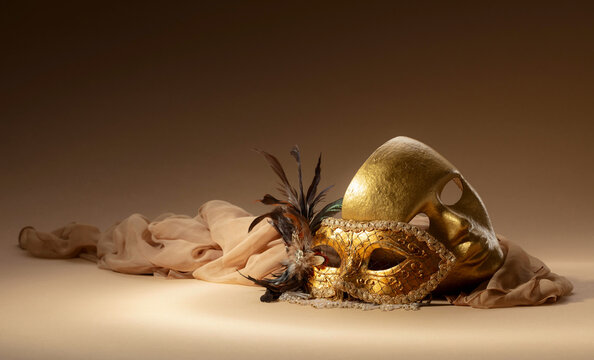 Golden Venetian carnival masks on a beige background.