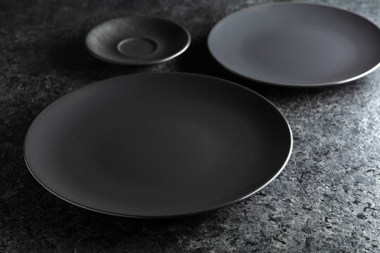 Black ceramic plates on a black stone table.