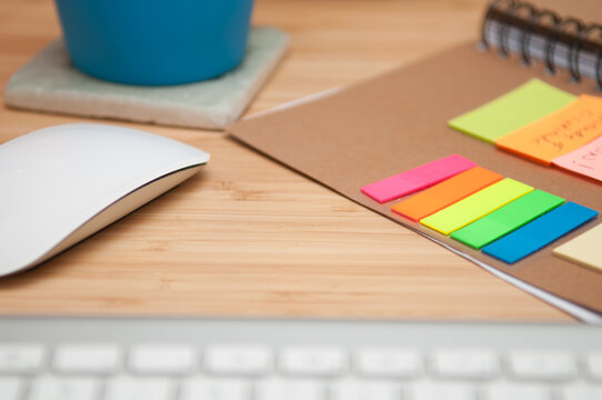 modern minimalist workspace with wireless mouse, keyboard and colorful sticky notes on wooden desk