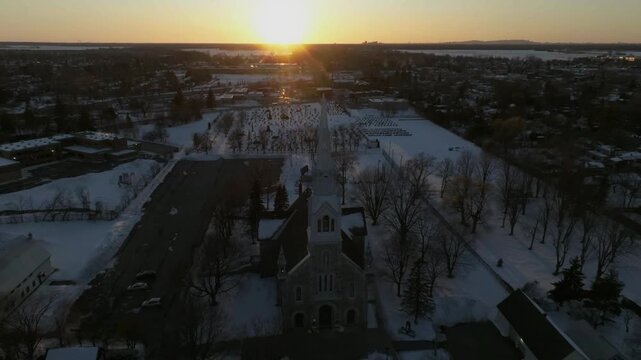 drone approaching from high to low to bigest church in chambly quebec canada in winter sun behind nice