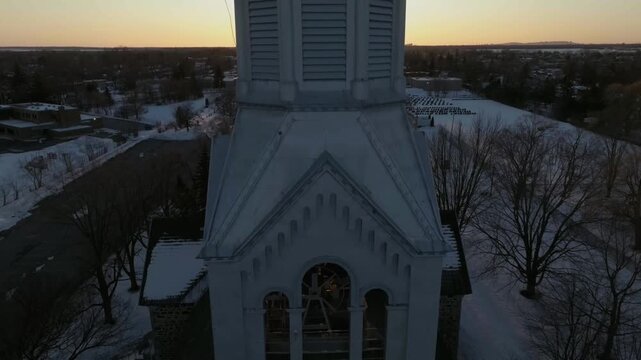 drone desending from tower to main bells of the church in chambly quebec canada in winter the front part n cementery