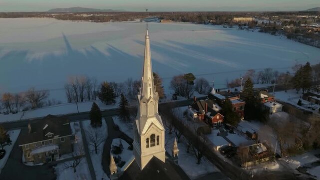 drone flying from behind the bigest church in chambly quebec canada towars the river richelieau in winter
