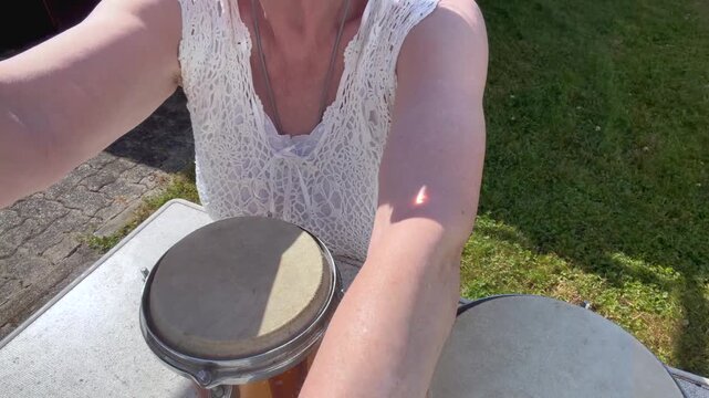 A woman kneels beside a garden table with two handcrafted Philippine hand drums featuring natural animal-hide drumheads. Close-up static shot