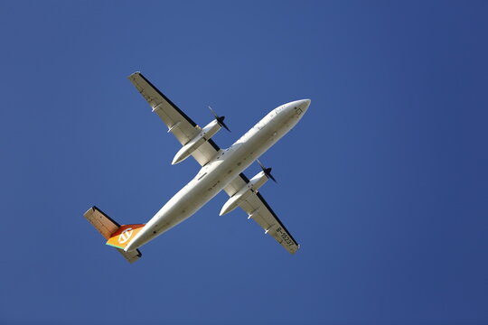 A UNI Air Dash 8-300 Flies Across Blue Sky.