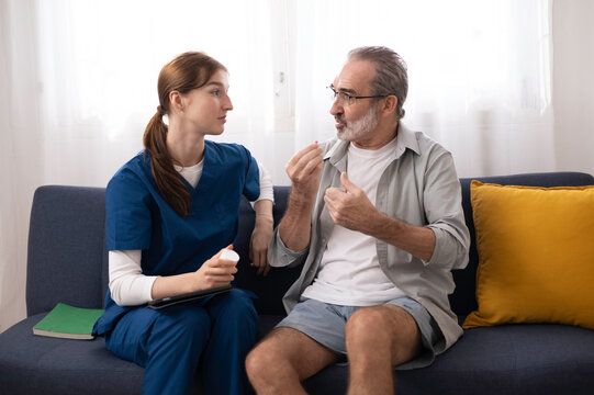 A private healthcare worker for an elderly man uses a digital tablet to monitor the patient's health at home, providing care and checking his physical condition.