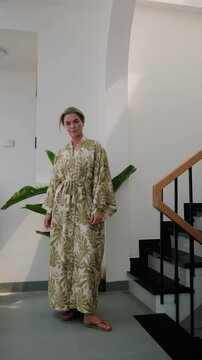 Elegant woman wearing luxury kimono robe in modern tropical home.