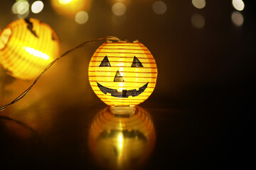 Obraz premium Festive Halloween Jack-O'-Lantern Pumpkin Lantern Glowing in Dark with Bokeh Background