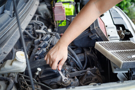 Hand of mechanic using a silver combination wrench to work on a pulley bolt