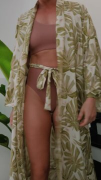 Elegant woman wearing luxury kimono robe over  swimsuit in modern tropical villa.
