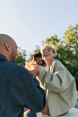 Obraz premium Laughing friends sharing drinks outside in daylight for summer social banner and lifestyle background design