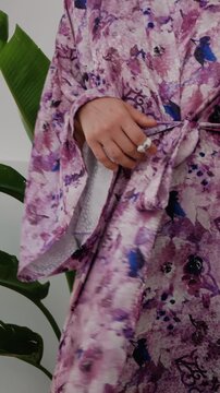 Elegant woman wearing luxury kimono robe in modern tropical home.