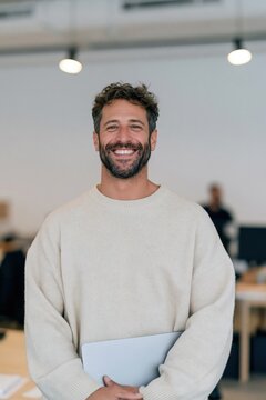 Smiling male office portrait full length of a man holding a laptop for team profile background and business website banner design
