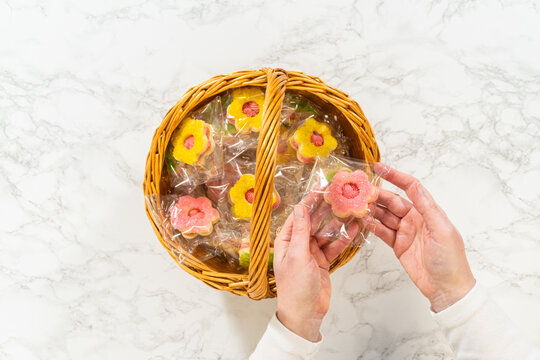 Hands Holding Two Packaged Cookies Over Basket