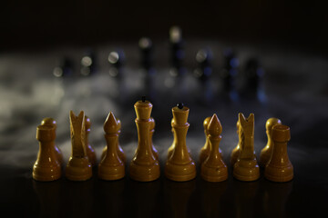 Chess Pieces on a Board in Dim Lighting with Smoke Background - Dramatic Strategy and Tactics Concept © alexkich