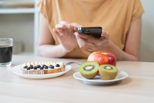 Low calorie healthy breakfast banner with woman hand holding fork eating banana blueberry sourdough toast kiwi and black coffee