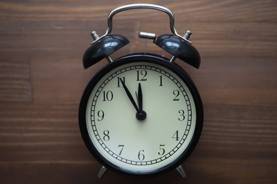 Vintage Black Alarm Clock on Wooden Table - Retro Timekeeping Concept